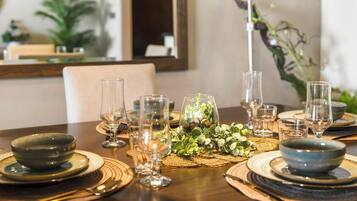 Een eettafel gedekt met diverse kommen, glazen en een middelpuntstuk met planten.