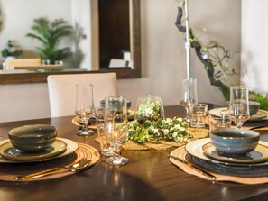 A dining table set with multiple bowls, glasses, and a centerpiece with greenery.