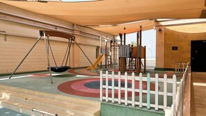 A children's play area with swings, slides, and a fenced play zone. - Anantara Sea & Burj Al Arab View / Private Beach (Dubai)