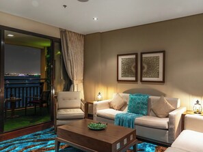 Sala de estar com sofá, poltrona, mesinha de centro e vista para uma varanda com guarda-corrimão.