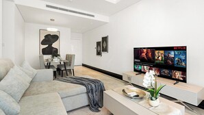 Ett modernt vardagsrum med en soffa, ett soffbord, en tv och en matplats.