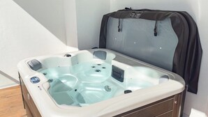 Ett bubbelbad med en kontrollpanel, en träbänk och ett skyddande överdrag.