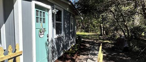 A house with a blue door, a welcome sign, and a wooden fence.