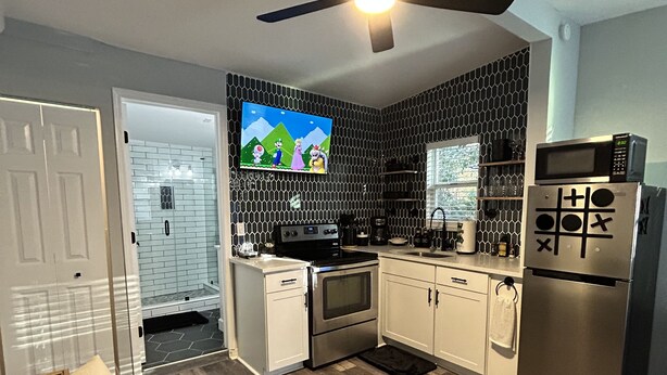 A modern kitchen with a built-in oven, microwave, and a TV mounted on the wall. - The Level Up Studio (Jacksonville)
