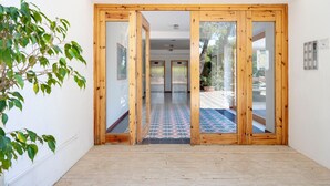 Un couloir avec des portes en bois, un sol carrelé et une plante en pot.