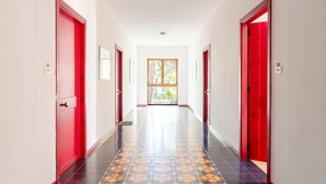 Un couloir avec des portes rouges, des carreaux de sol à motifs et des tableaux encadrés accrochés aux murs.