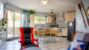 Une cuisine moderne avec des meubles blancs, un réfrigérateur noir et un coin repas agrémenté d’une nappe jaune.