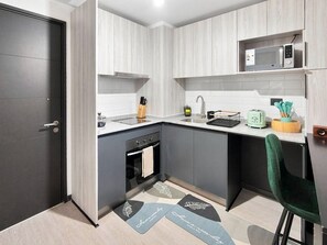 A compact kitchen with a microwave, sink, and stove. - Oceana Suites La Florida Friolan Roa (Santiago)