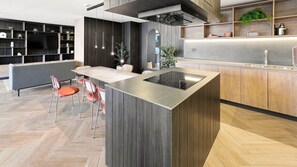 A modern kitchen with a central island, wooden cabinetry, and a herringbone floor pattern. - Oceana Suites La Florida Friolan Roa (Santiago)