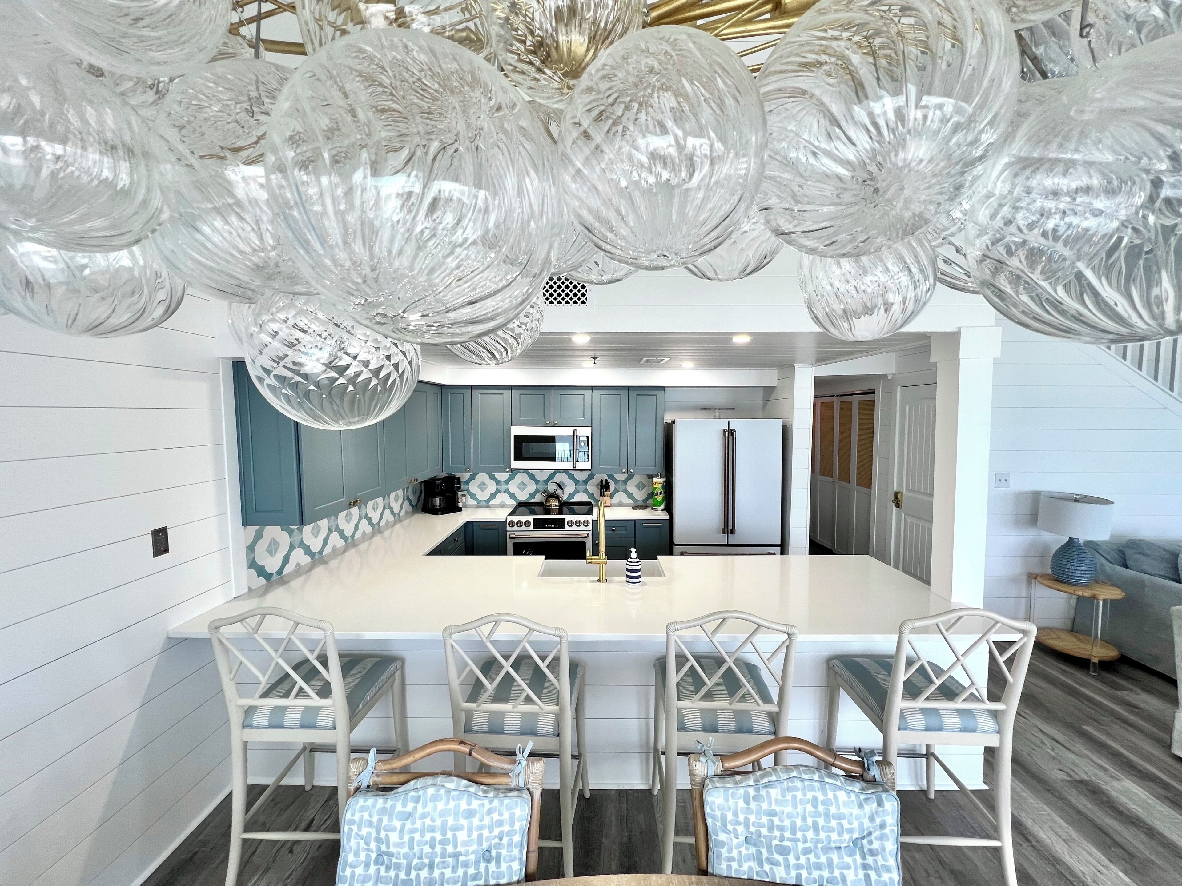 A modern kitchen with a central island, bar stools, and a refrigerator.