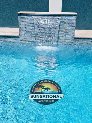A swimming pool with a waterfall feature and a logo for 'Sunsational' at the bottom. - Villa Flores- New Modern Luxury Villa within walking distance from ANR Airport. (Bon Accord)