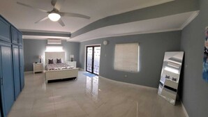 A bedroom with a bed, a ceiling fan, a wardrobe, and a window with blinds. - Villa Flores- New Modern Luxury Villa within walking distance from ANR Airport. (Bon Accord)
