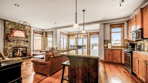 Una cocina amplia con armarios de madera, una chimenea de piedra y ventanas grandes con vistas al exterior.