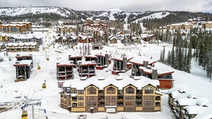 Une station de ski enneigée, dotée de plusieurs bâtiments, de remontées mécaniques et offrant un paysage montagneux en toile de fond.