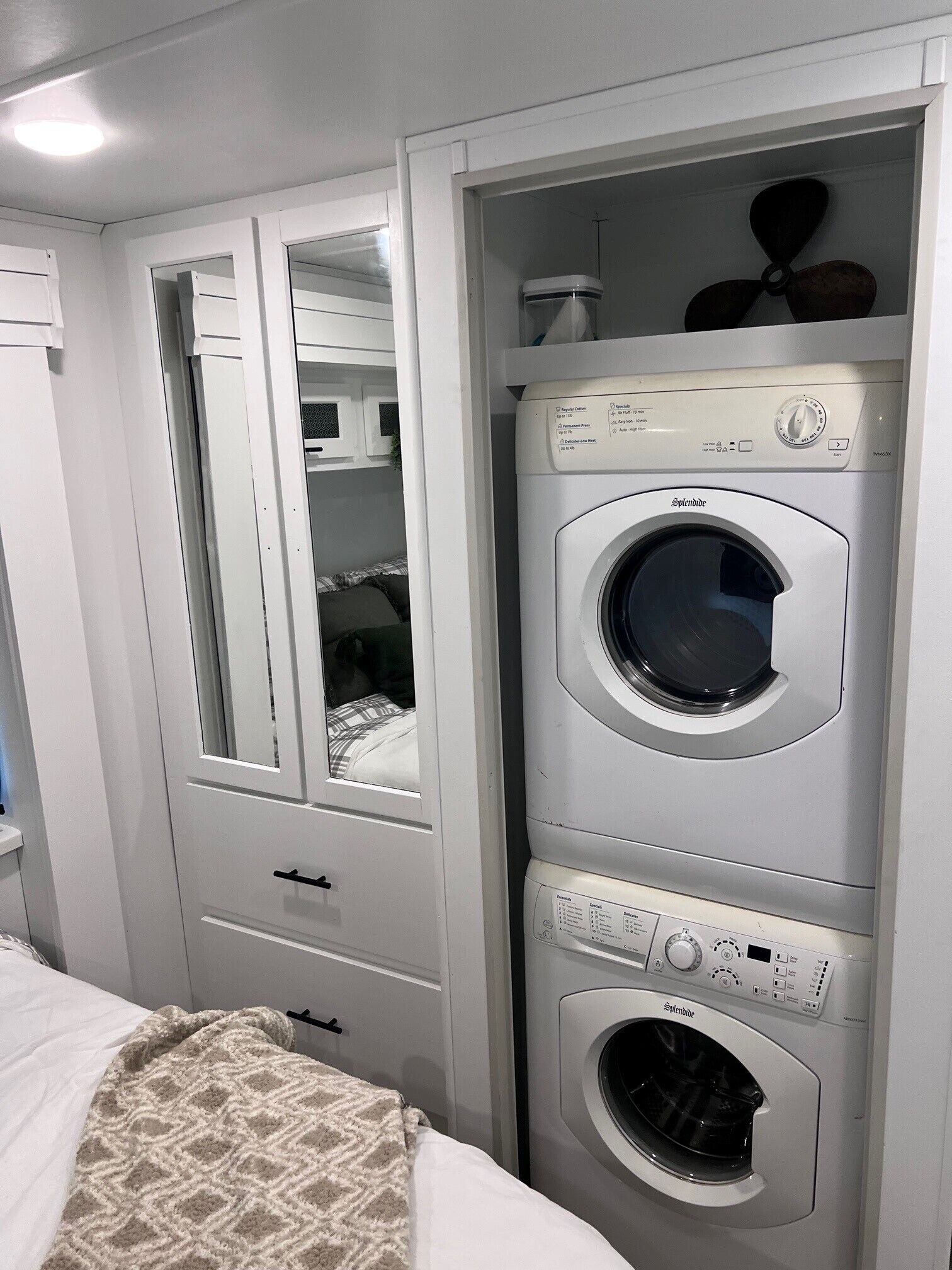 A compact laundry room with a front-loading washing machine, a dryer, and a mirror above the dryer.