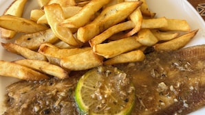 A plate with a fish and fries. - Hôtel Finio (Joal-Fadiout)