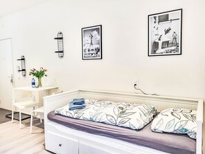 A bedroom with a bed, a desk, and a chair. There are three framed pictures on the wall. - White Locarno Apt.1 by Interhome (Locarno)