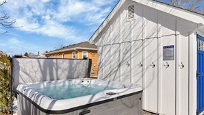 Un jacuzzi al aire libre frente a un edificio con una puerta azul y un cartel que indica normas de seguridad.