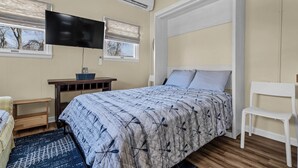 Un dormitorio con cama, televisión, escritorio y silla.
