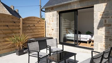 A stone house with a glass door leading to a bedroom.