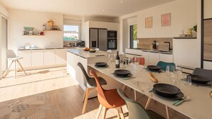 Een moderne keuken met een centraal eiland, een eetgedeelte en geïntegreerde apparatuur.