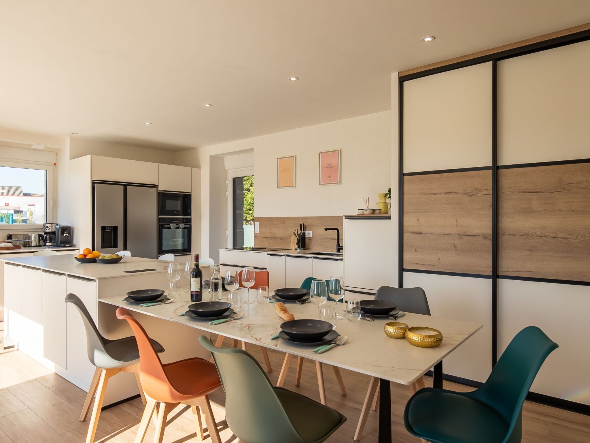 A modern kitchen with a central island, dining table, and chairs.