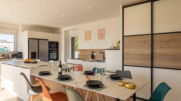 A modern kitchen with a central island, dining table, and chairs.
