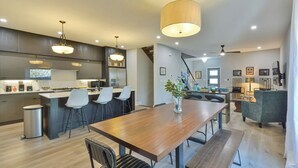 A modern kitchen with bar stools, a wooden dining table, and pendant lighting. - Veranda with skyline views (Atlanta)