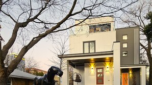 A modern two-story house with a visible front porch, a small garden, and a sculpture of a horse. - Veranda with skyline views (Atlanta)