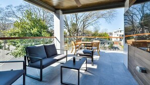 A modern outdoor seating area with a sofa, chairs, and a table, overlooking a residential neighborhood. - Veranda with skyline views (Atlanta)