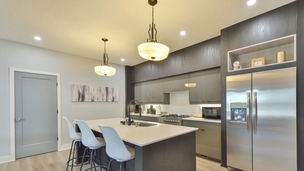 A modern kitchen with a central island, bar stools, stainless steel appliances, and pendant lighting. - Veranda with skyline views (Atlanta)