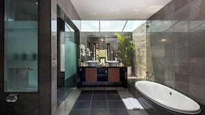 Ein modernes Badezimmer mit einer großen Badewanne, zwei Waschbecken und einer Duschkabine aus Glas.