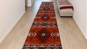 A hallway with a patterned rug, a sofa, and a bench.