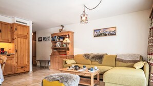 Ein gemütliches Wohnzimmer mit einem gelben Sofa, einem grünen Sofa, einem Holzkabinett und einem kleinen Tisch mit Teeservice.