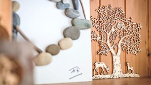 Eine Holzschnitzerei von einem Baum mit Darstellungen von Hirschen und Eulen, vor einem Holzhintergrund.