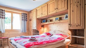 Ein Schlafzimmer aus Holz mit einem Bett, einem Sessel und eingebauten Holzschränken.