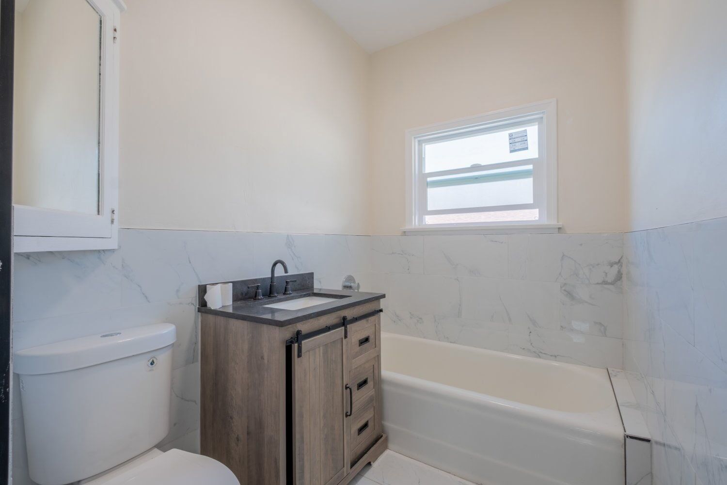 A bathroom with a toilet, sink, vanity, and bathtub.