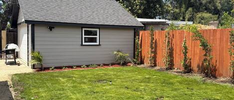 A residential property with a well-maintained lawn, a wooden fence, and a house with a grey roof.