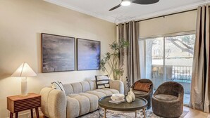 Un salon comprenant un canapé, des fauteuils, une table basse, une lampe et des œuvres d’art accrochées au mur.