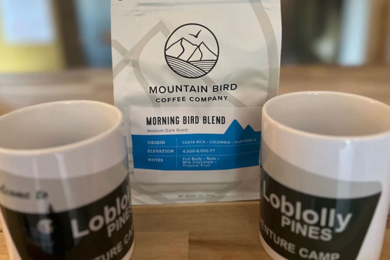 Deux tasses portant l’inscription « Loblolly Pines » et un sac de café « Mountain Bird Coffee Company Morning Bird Blend », avec des informations sur son origine et son altitude.