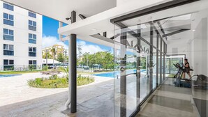 Un edifici modern amb façana de vidre, piscina exterior i equipament esportiu.