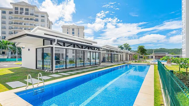 Un hotel modern amb piscina, habitacions amb vidre i vistes als edificis circumdants.