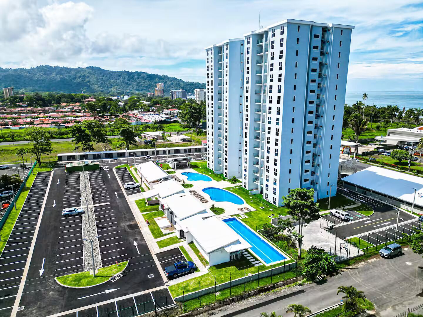 A high-rise building with a swimming pool and a parking lot.
