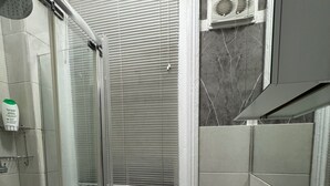 Ein Badezimmer mit Glasdusche, Toilette und Waschbecken mit Spiegel.