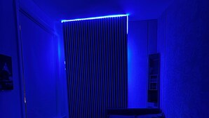 Ein kleiner, schummrig beleuchteter Raum mit einem Bett, einem Schreibtisch und einem Fenster mit Jalousien.