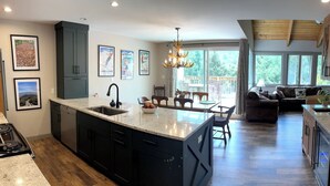 Una cocina moderna con una isla grande, muebles oscuros y un comedor con candelabro.