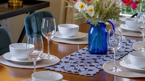 A dining table set with white plates, bowls, and wine glasses, a blue vase with flowers, and a chandelier. - Fendalton Comfort Stylish and Convenient with Carpark (Christchurch)