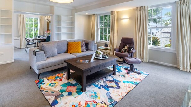 A modern living room with a grey sofa, a dark coffee table, and a colorful rug. - Fendalton Comfort Stylish and Convenient with Carpark (Christchurch)