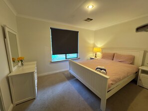 A bedroom with a bed, bedside tables, a nightstand, a lamp, a window with blinds, a mirror, and a dresser. - Coastal retreat in Secret Harbour (Secret harbour)