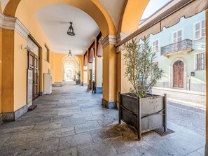 A corridor with arches, a potted plant, and a building with a balcony in the background. - Barbero by Interhome (Costigliole d'Asti)
